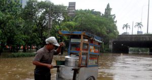 Warga melintas saat banjir yang merendam kawasan Cawang, Jakarta, Rabu (1/1). Banjir tersebut membuat lalu lintas kawasan Cawang lumpuh. Foto : Ricardo