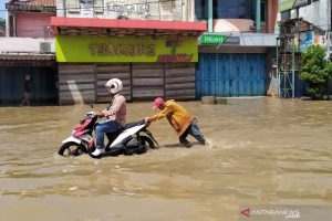 Pengendara motor melintasi genangan banjir di Jalan Raya Dayeuhkolot, Kabupaten Bandung. Foto: ANTARA/Bagus Ahmad Rizaldi